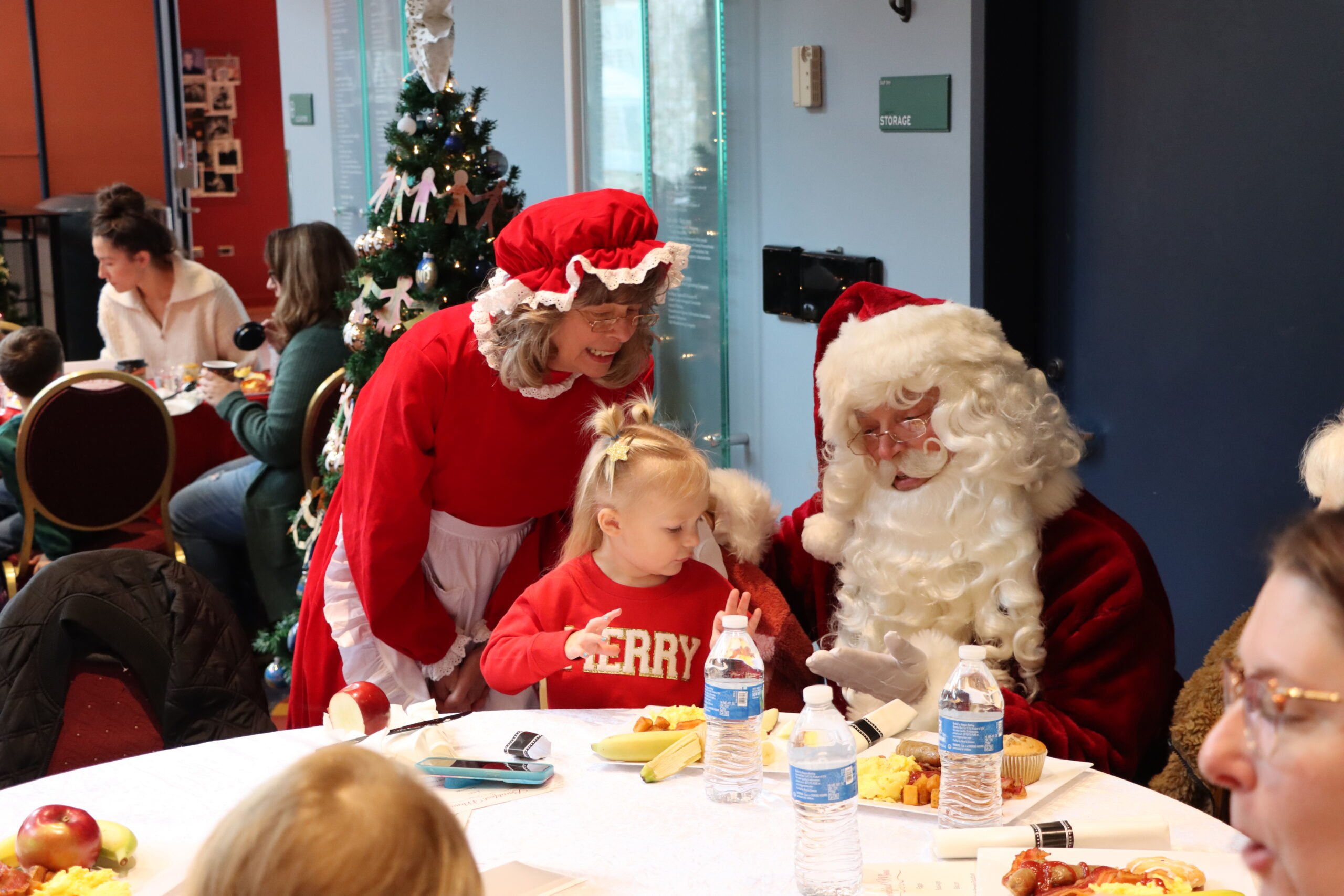 A small child eats breakfast with Santa and Mrs. Claus during Breakfast With Santa at Whitaker Center in 2024.
